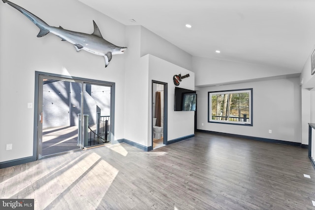 empty room with high vaulted ceiling, baseboards, and wood finished floors