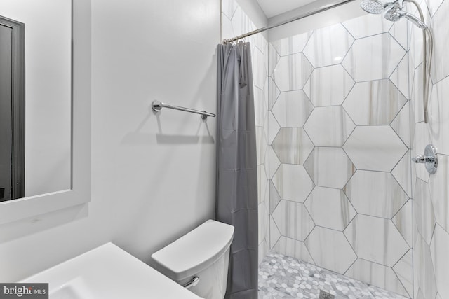 full bath with a tile shower and toilet