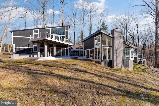 rear view of house with a yard, a chimney, and a wooden deck