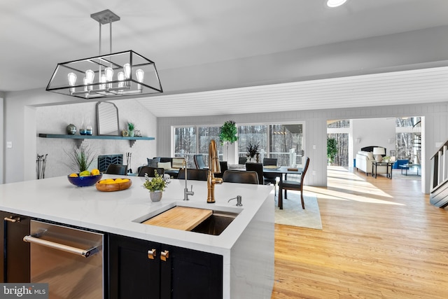 kitchen with pendant lighting, light countertops, light wood-style floors, open floor plan, and dark cabinets