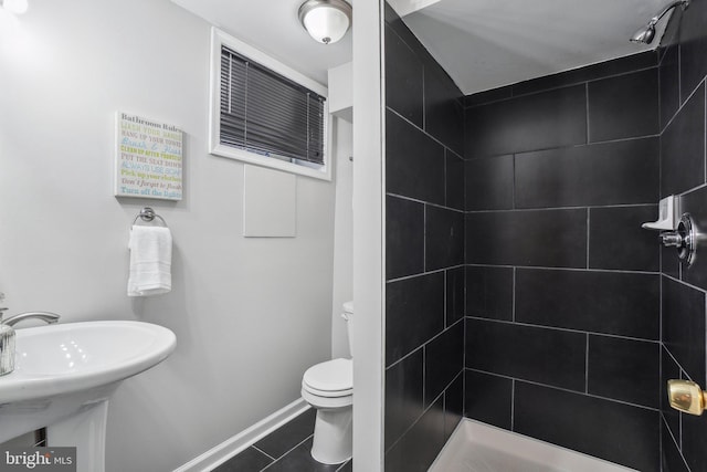 bathroom with tile patterned floors, tiled shower, and toilet