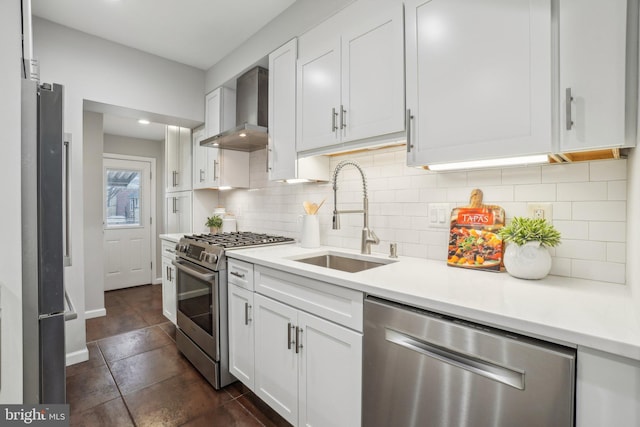 kitchen featuring sink, tasteful backsplash, stainless steel appliances, white cabinetry, and wall chimney range hood