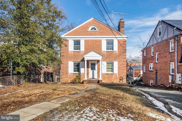 view of front of property with a chimney, fence, and brick siding