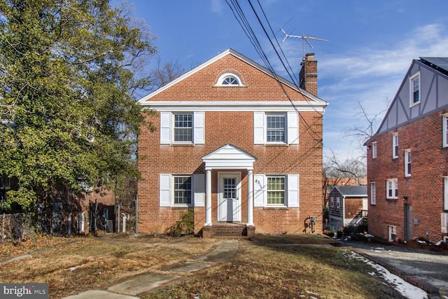 view of front of home with brick siding and a chimney