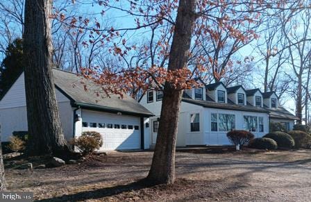 cape cod home featuring an attached garage