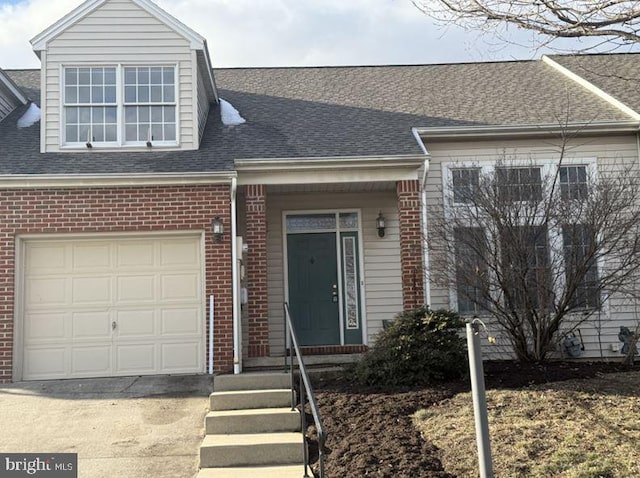 view of property with brick siding, concrete driveway, a garage, and a shingled roof