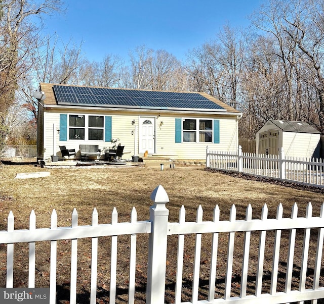 view of front of house featuring a front lawn, a patio area, a shed, and solar panels