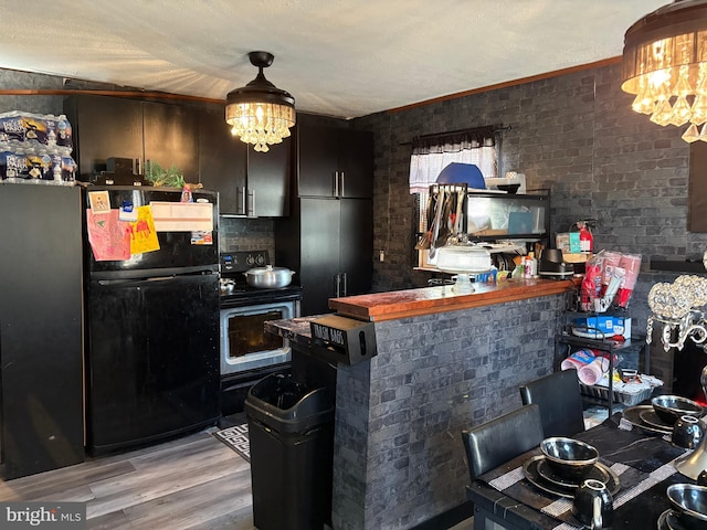 kitchen featuring light hardwood / wood-style flooring, black refrigerator, range with electric cooktop, dark brown cabinetry, and a chandelier