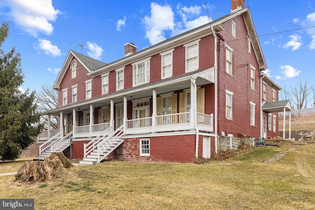 view of front of home featuring a chimney, a front lawn, a porch, and brick siding