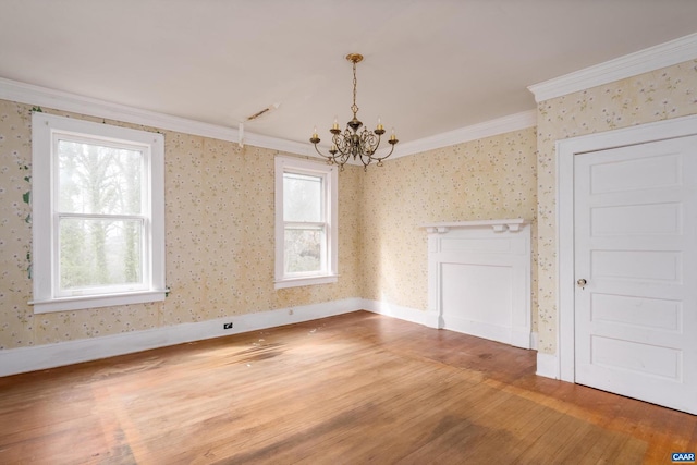 empty room with a notable chandelier, wood finished floors, baseboards, wallpapered walls, and crown molding