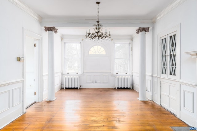 unfurnished dining area featuring radiator, crown molding, and wood finished floors