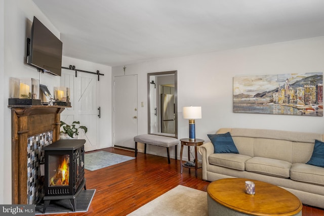 living room with dark hardwood / wood-style floors, a barn door, and a wood stove