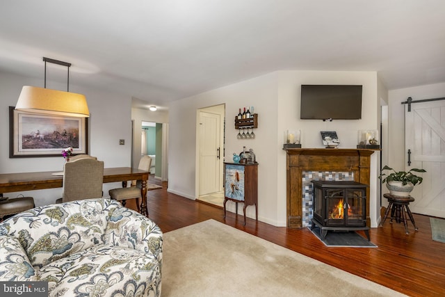 living room featuring dark hardwood / wood-style floors, a barn door, and a wood stove