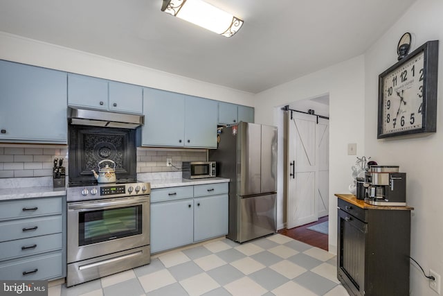 kitchen with blue cabinets, a barn door, backsplash, and appliances with stainless steel finishes