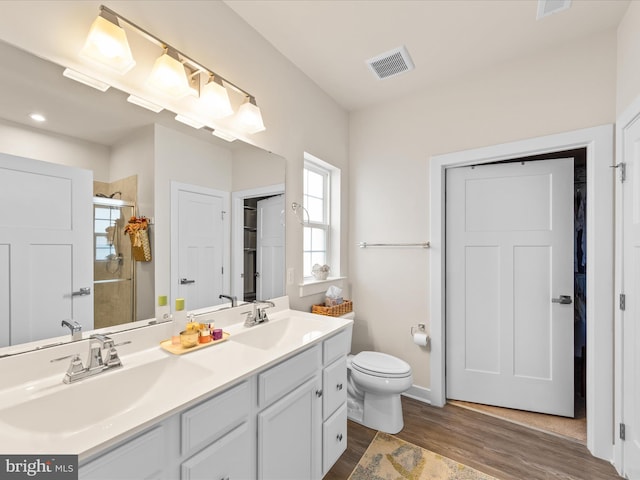 bathroom featuring a shower with door, vanity, hardwood / wood-style floors, and toilet