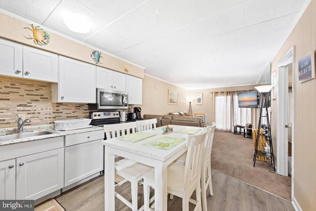 kitchen with light countertops, stainless steel microwave, a sink, and white cabinetry