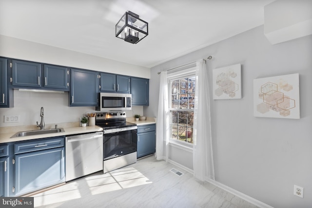 kitchen with blue cabinets, visible vents, appliances with stainless steel finishes, and a sink