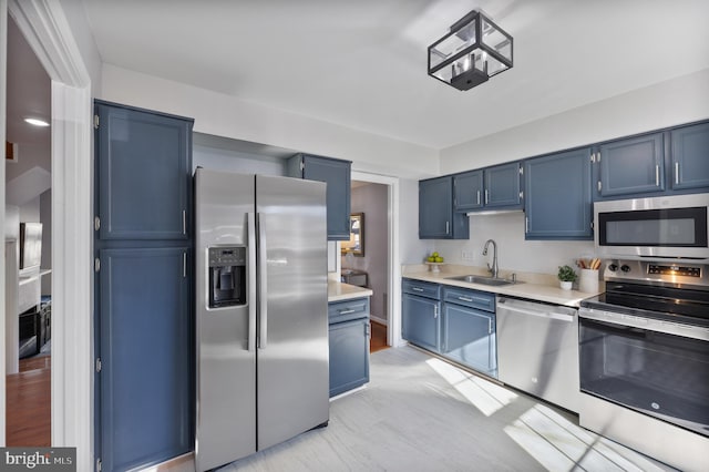 kitchen featuring light countertops, blue cabinetry, appliances with stainless steel finishes, and a sink