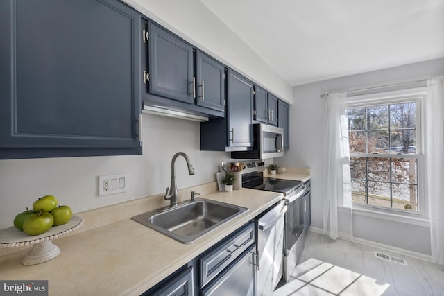 kitchen featuring blue cabinets, visible vents, a sink, stainless steel appliances, and light countertops