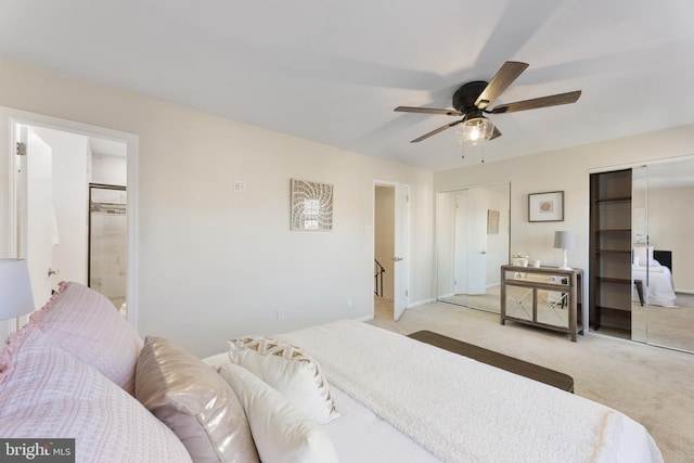 bedroom featuring ceiling fan, ensuite bathroom, carpet, and multiple closets