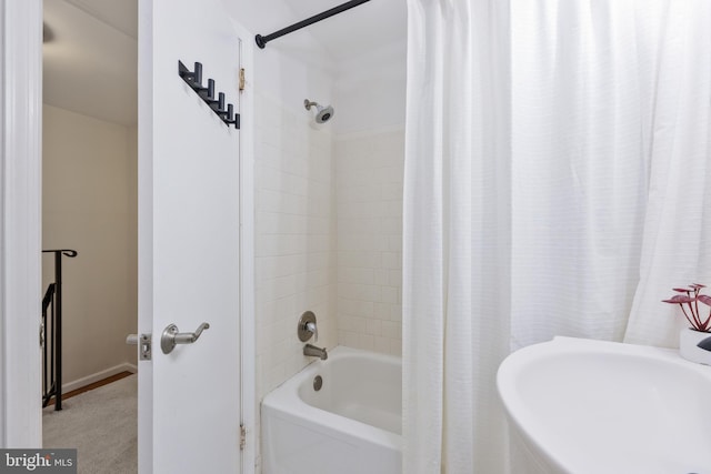 bathroom featuring shower / tub combo, baseboards, and a sink