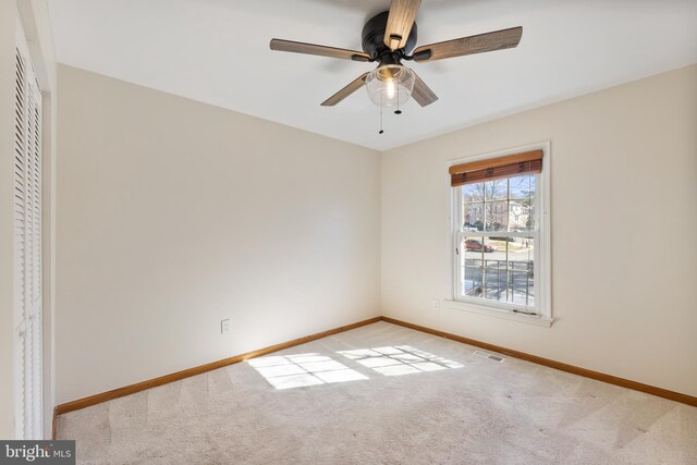 unfurnished room with visible vents, baseboards, carpet, and a ceiling fan