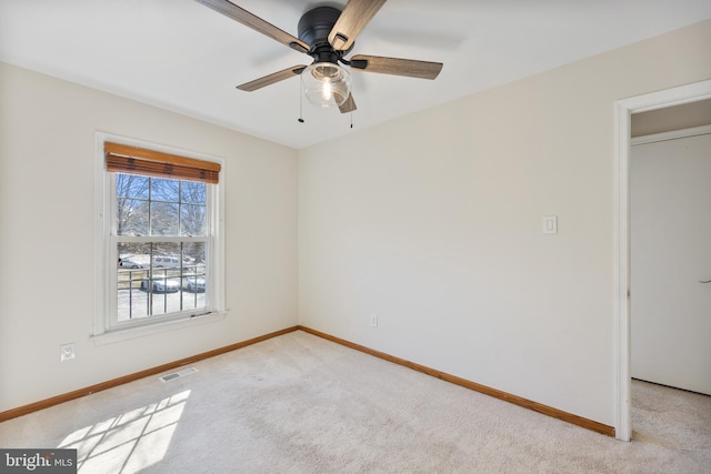 spare room featuring visible vents, light colored carpet, baseboards, and ceiling fan