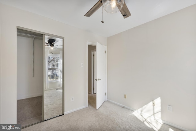 unfurnished bedroom featuring ceiling fan, carpet, a closet, and baseboards