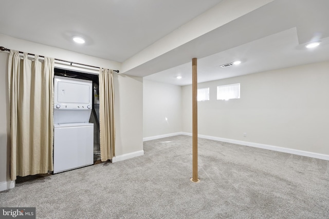 below grade area with visible vents, carpet flooring, stacked washer / drying machine, and baseboards