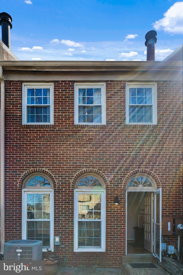 view of front of house featuring cooling unit and brick siding