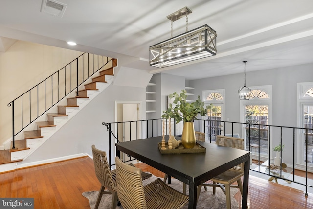 dining space with visible vents, baseboards, a notable chandelier, and wood finished floors