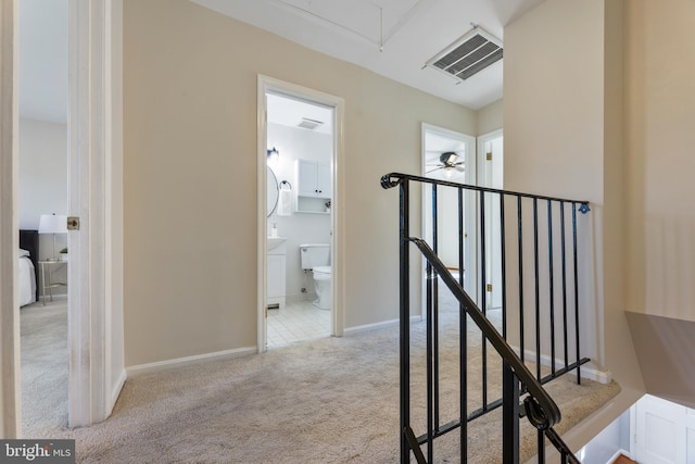 corridor featuring carpet, visible vents, baseboards, attic access, and an upstairs landing