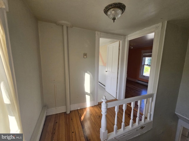 corridor with hardwood / wood-style flooring and a baseboard heating unit