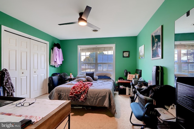 bedroom featuring a ceiling fan, a closet, visible vents, and light colored carpet