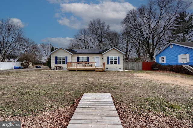 rear view of property featuring solar panels, fence, a yard, crawl space, and a wooden deck