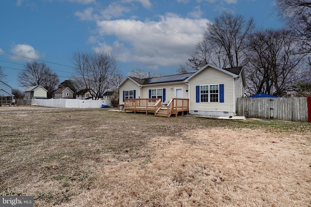 view of front of house with solar panels, crawl space, fence private yard, a wooden deck, and a front yard