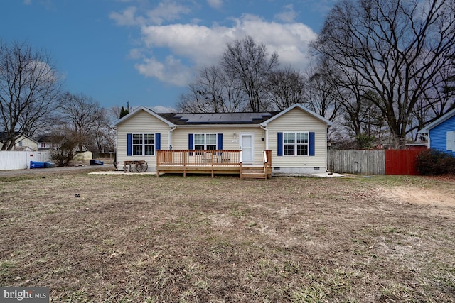 back of house with crawl space, fence, a wooden deck, and solar panels