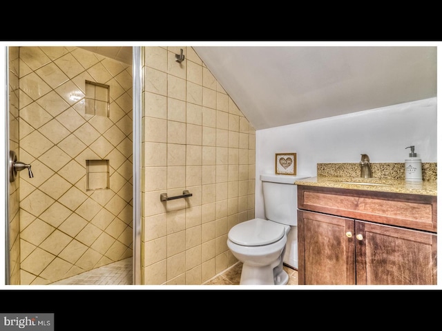 bathroom with lofted ceiling, tile walls, vanity, toilet, and a shower with door