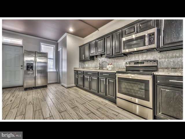 kitchen featuring light hardwood / wood-style floors, crown molding, stainless steel appliances, light stone countertops, and decorative backsplash