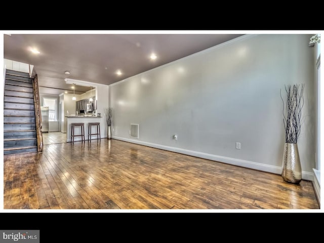 unfurnished living room featuring dark wood-type flooring and crown molding