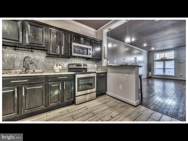 kitchen featuring sink, backsplash, light wood-type flooring, pendant lighting, and stainless steel appliances