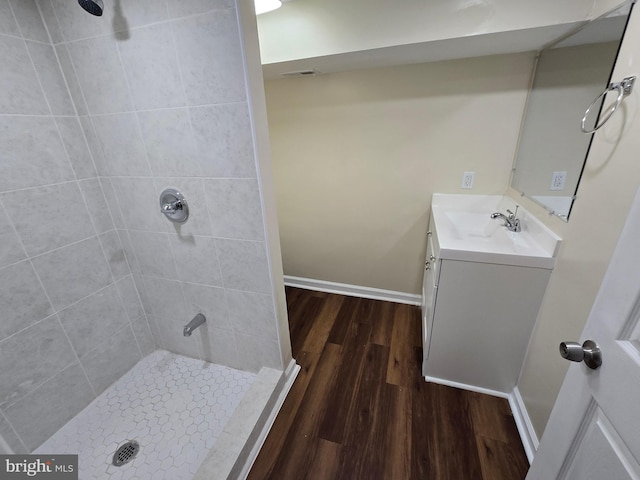 bathroom featuring hardwood / wood-style flooring, tiled shower, and vanity