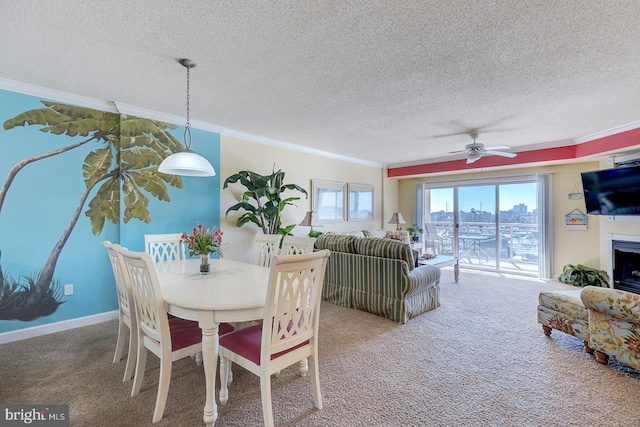 dining room with a textured ceiling, crown molding, a fireplace, and carpet flooring