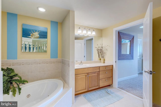 bathroom featuring tile patterned flooring, a tub with jets, baseboards, and vanity