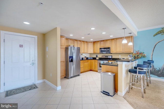 kitchen with dark countertops, a breakfast bar area, a peninsula, hanging light fixtures, and stainless steel appliances