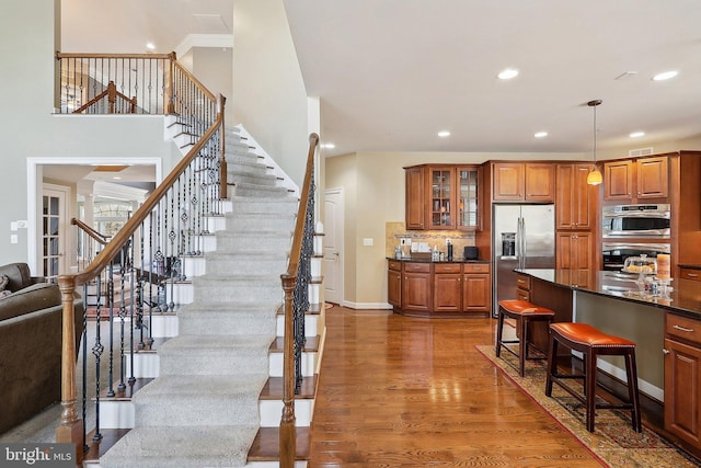 kitchen featuring brown cabinets, a breakfast bar area, stainless steel appliances, dark countertops, and wood finished floors