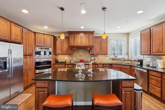 kitchen with stainless steel appliances, a breakfast bar, a sink, a center island, and light wood finished floors