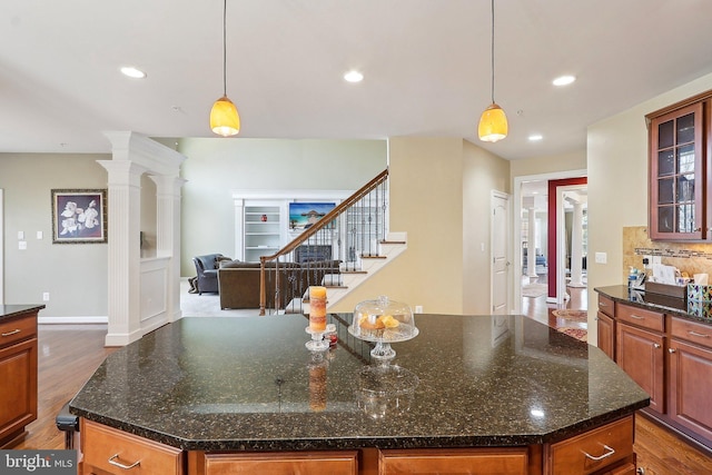 kitchen with decorative backsplash, a kitchen island, glass insert cabinets, wood finished floors, and recessed lighting