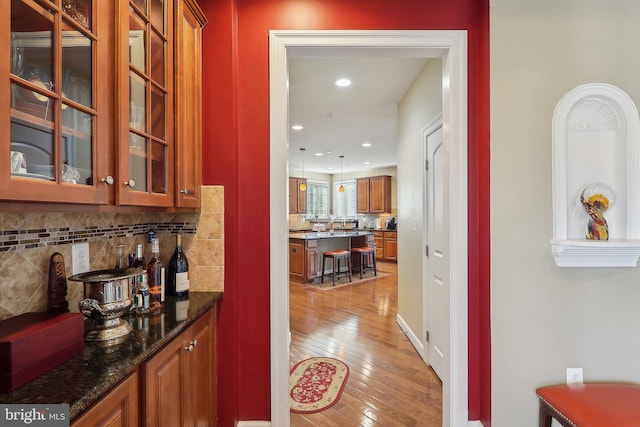 interior space featuring light wood-type flooring, recessed lighting, backsplash, and hanging light fixtures