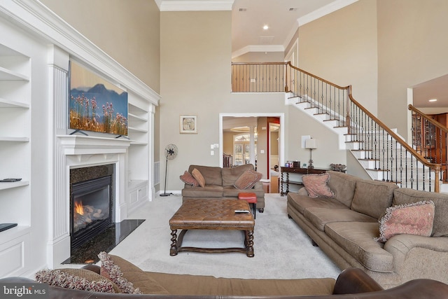 living room featuring stairs, crown molding, carpet floors, built in shelves, and a fireplace